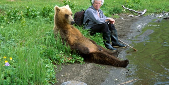 Person sitting with a brown bear.